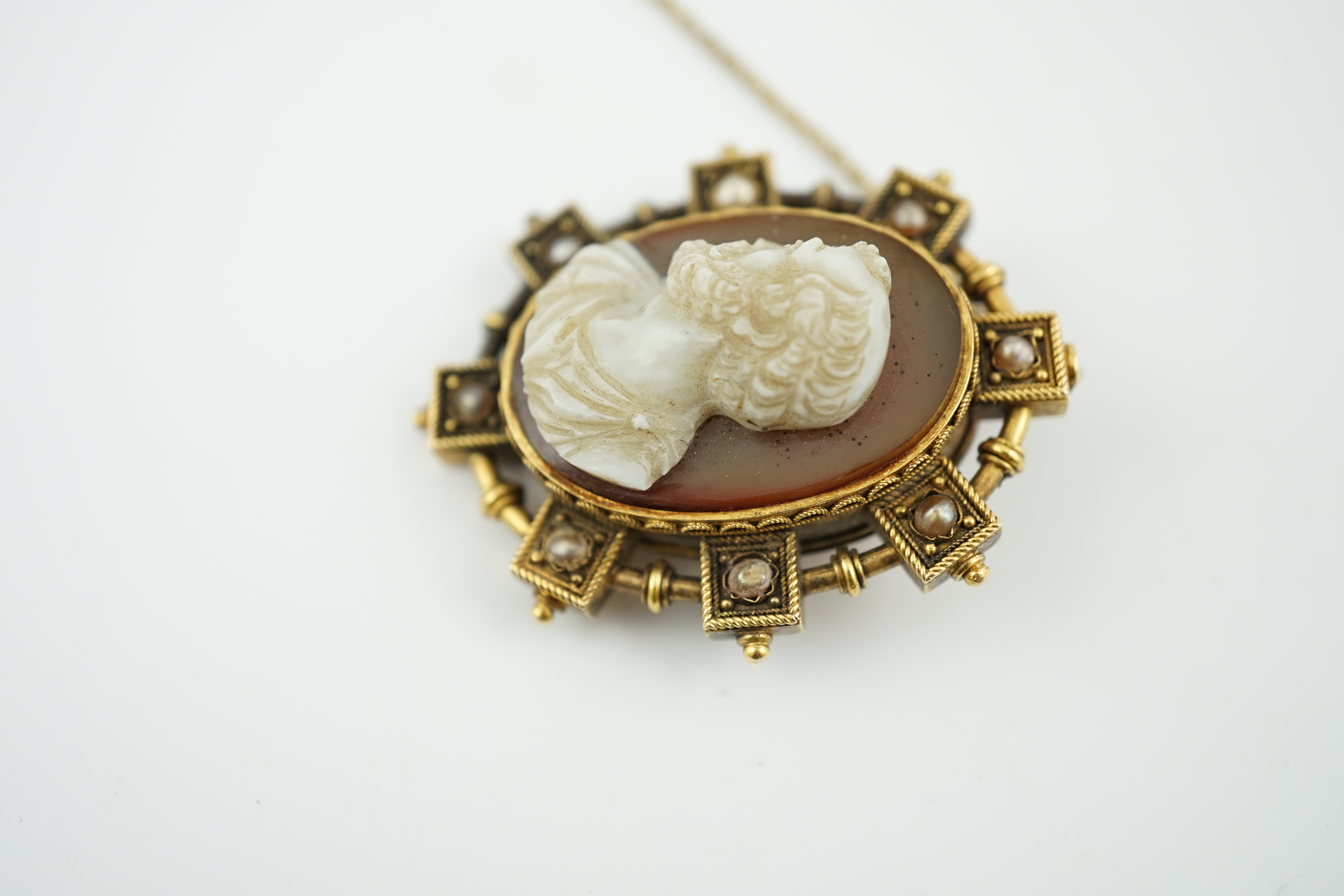 A Victorian gold and split pearl mounted oval hardstone cameo brooch, carved with the bust of a gentleman to dexter